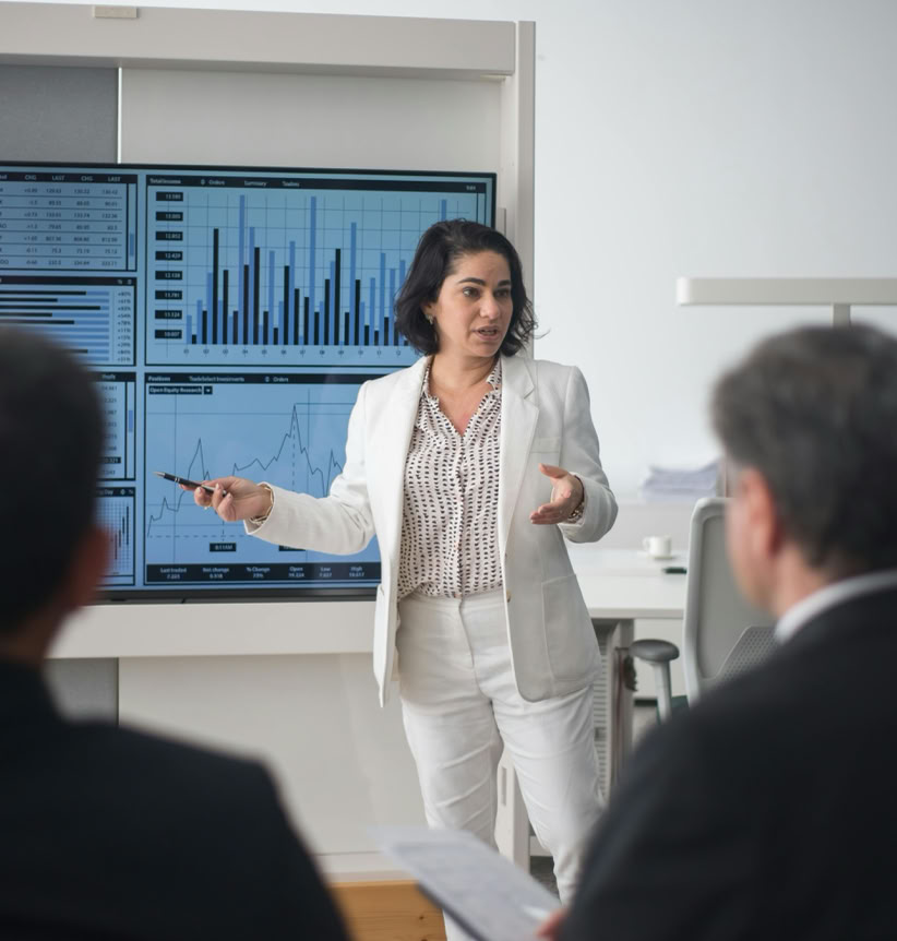 Professional woman presenting stock market data in a modern office setting.