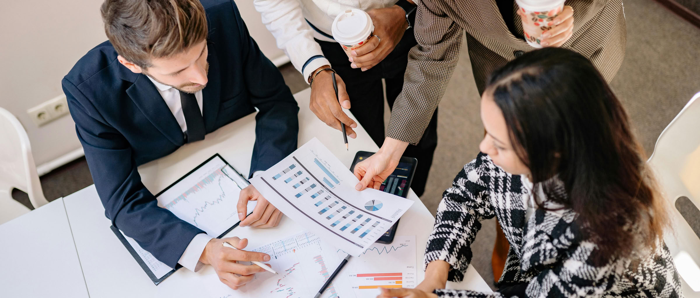 A diverse team in business attire collaborates over graphs and charts for a successful project.